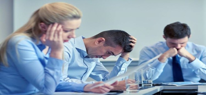 People at Table in blue shirts looking frustrated