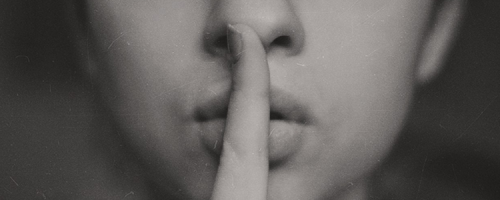 Woman with finger to lips shhh